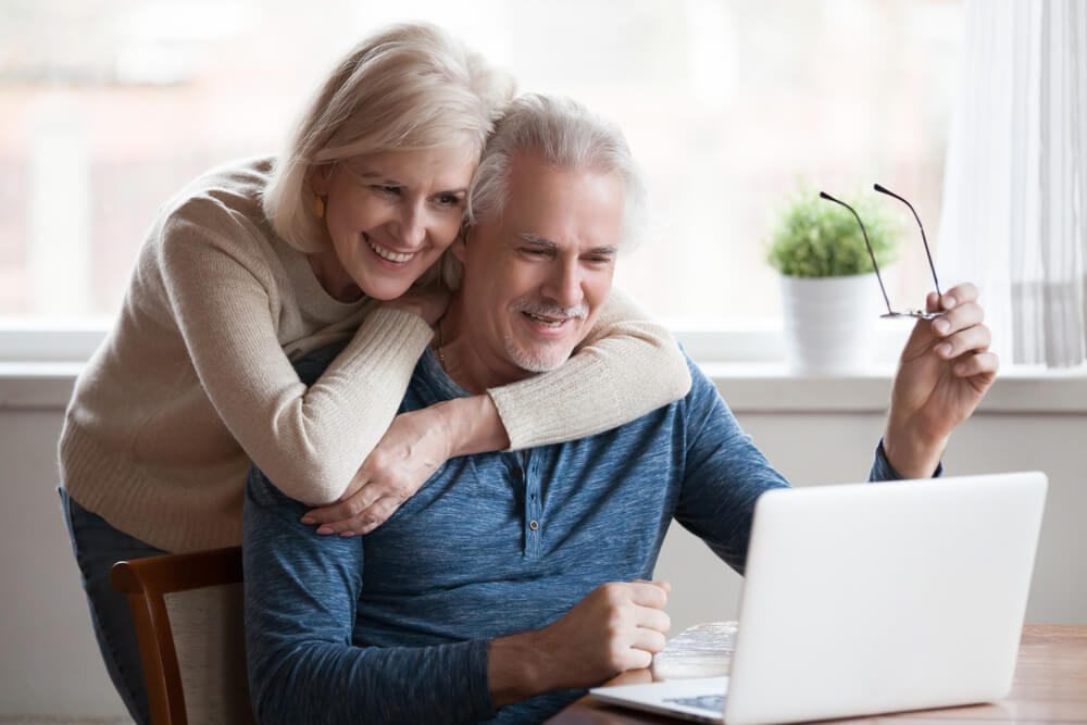 Middle Aged Happy Couple Embracing Using Laptop Together | Diamond Vision