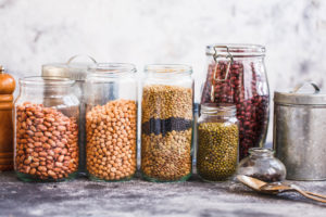 Collection of grain products lentils peas soybeans and red beans in storage jars over on kitchen rural table Vegetarian products | Diamond Vision