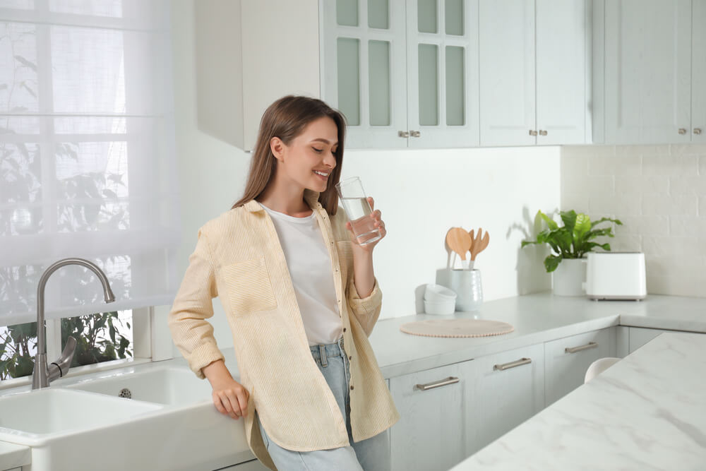 Woman Drinking Tap Water From Glass in Kitchen