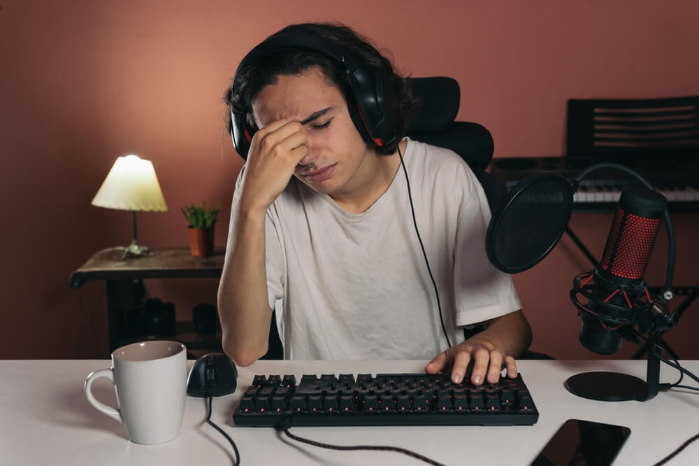 Young Gamer Boy With Headache Touching His Face Out of Frustration or Because He Has Eyestrain From Prolonged Screen Time