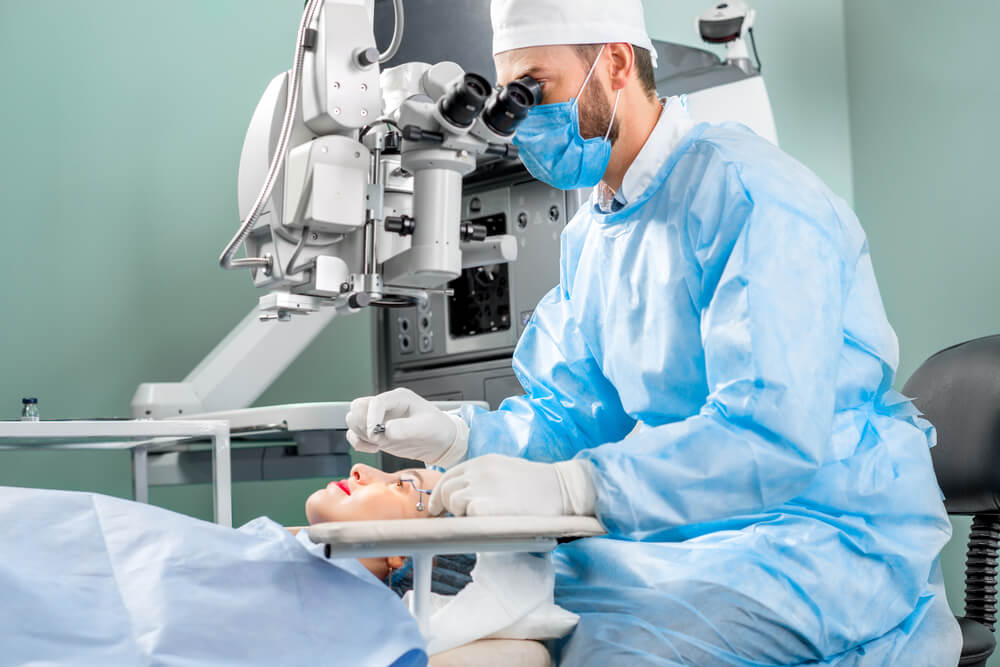 A surgeon operating eye of female patient using surgical microscope in the operating room/